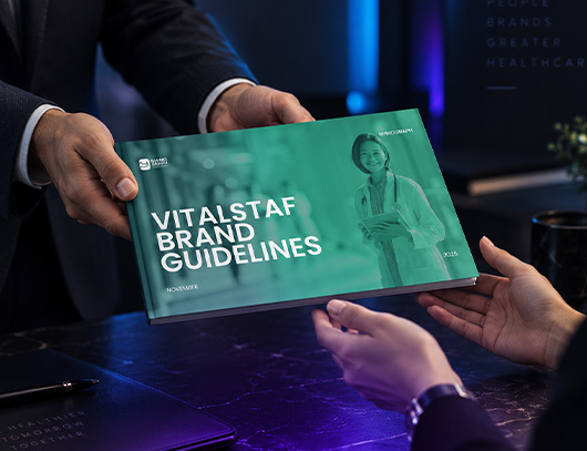 Vitalstaf brand guidelines book handed across a desk